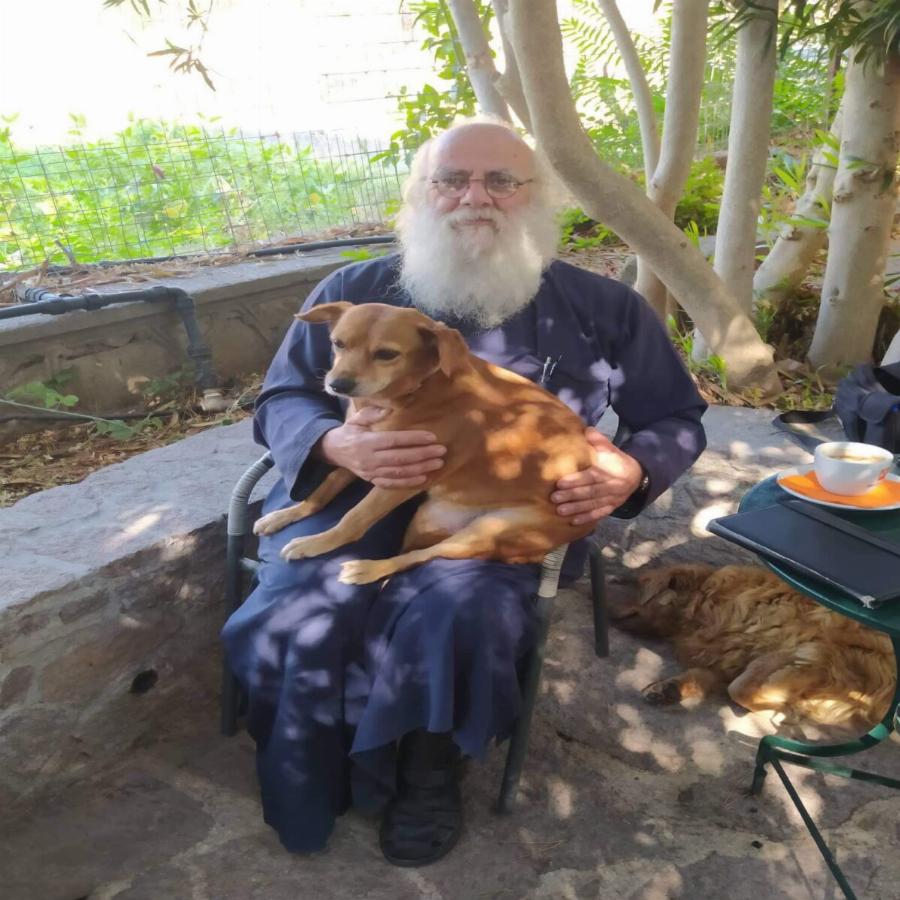 Ένας ιερέας διαφορετικός από τους άλλους στην Λέσβο: Κουβαλάει στα χέρια μια σκυλίτσα που έχει πρόβλημα με τη μέση της