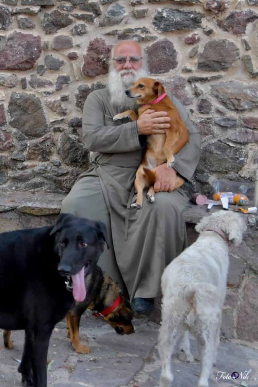 Ένας ιερέας διαφορετικός από τους άλλους στην Λέσβο: Κουβαλάει στα χέρια μια σκυλίτσα που έχει πρόβλημα με τη μέση της